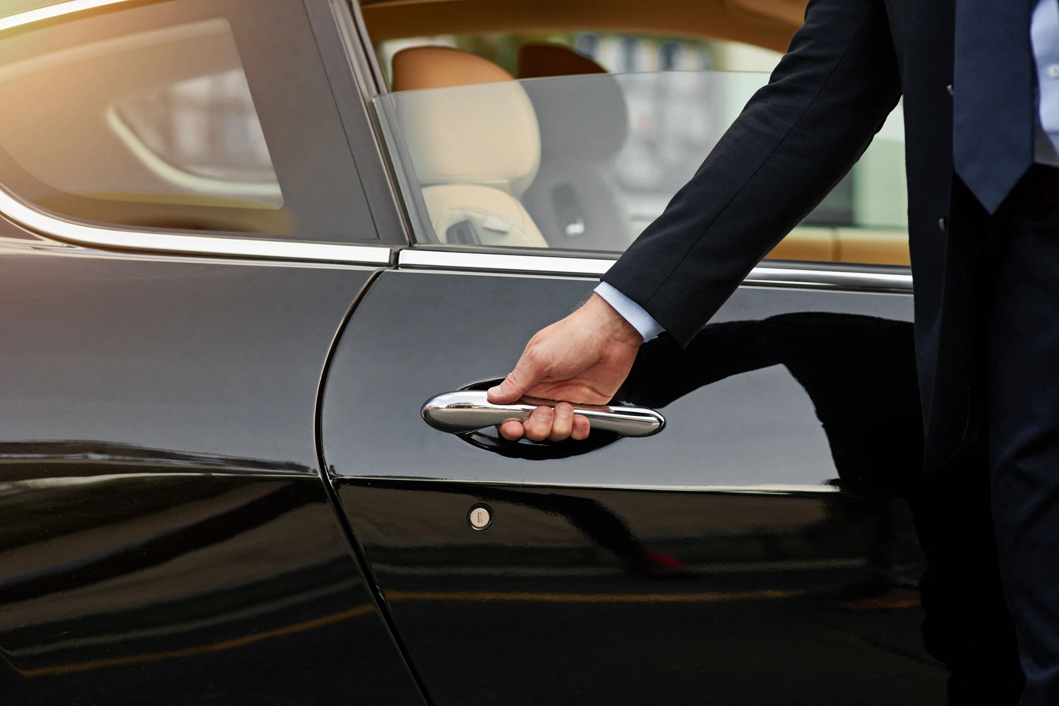 Professional chauffeur opening a car door for a guest